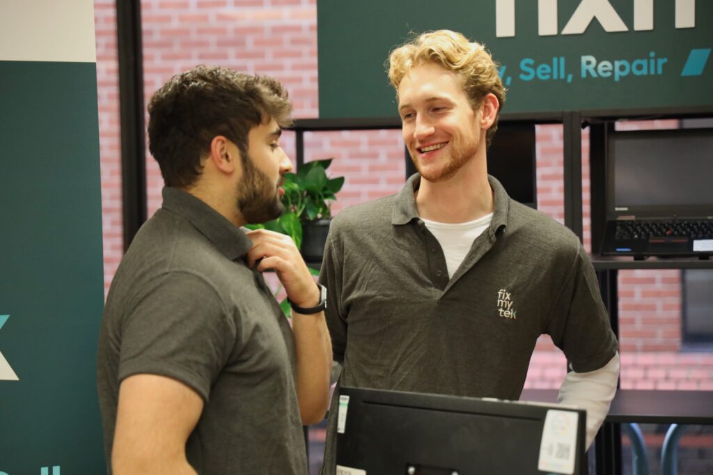 Two people wearing FixMyTek polo shirts chatting