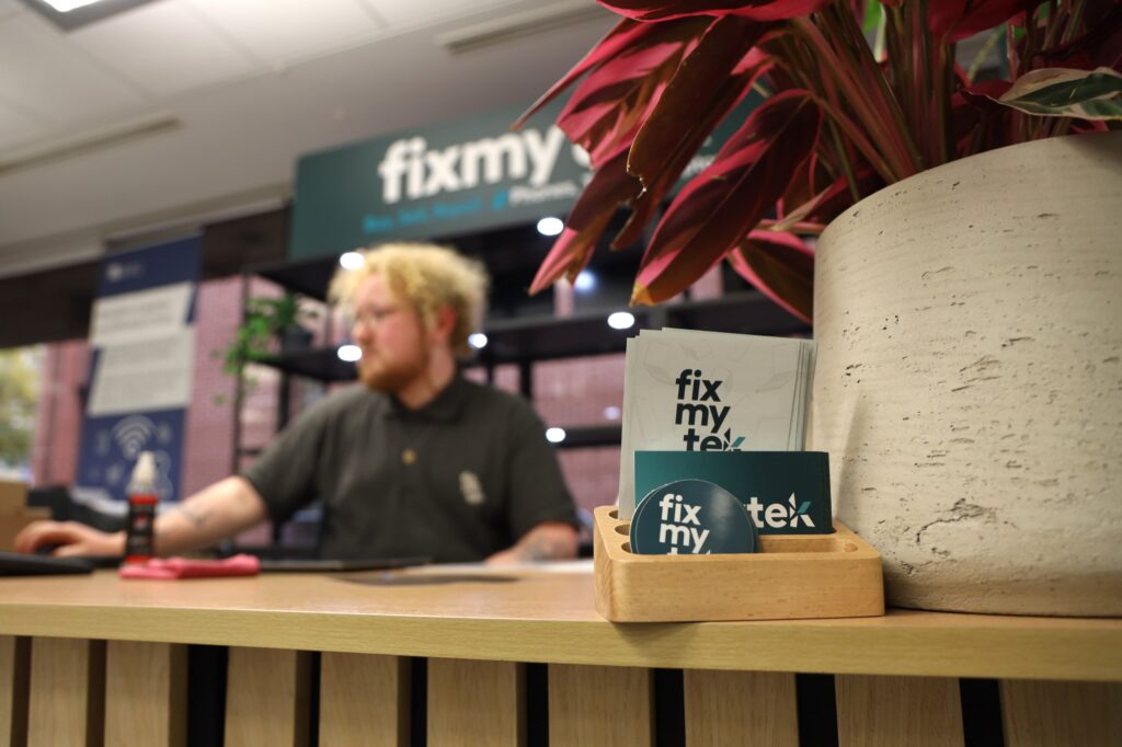 Out of focus image showing FixMyTek business cards on shop desk